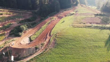 Drone-shot-of-motocross-riders-riding-motorbikes-on-dirt-park-track-over-the-left-turn-and-jump-fast