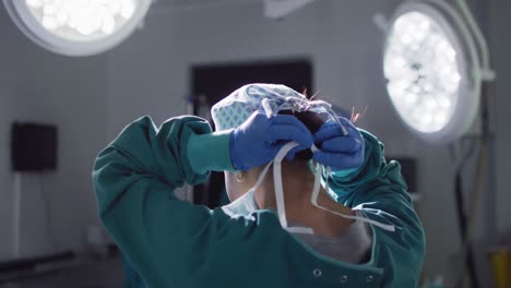 video of rear view of asian female surgeon tying face mask in operating theatre