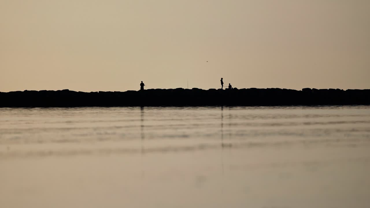 Silhouette of people fishing at sunset