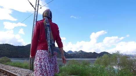 woman walking on train tracks, scenic landscape