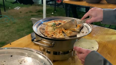 man taking a slice of pizza on a porcelain plate with a metal spatula