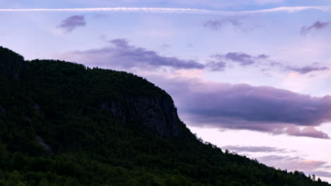 time-lapse-of-sun-setting-behind-mountain-range-creating-beautiful-purple-colored-clouds-floating-by