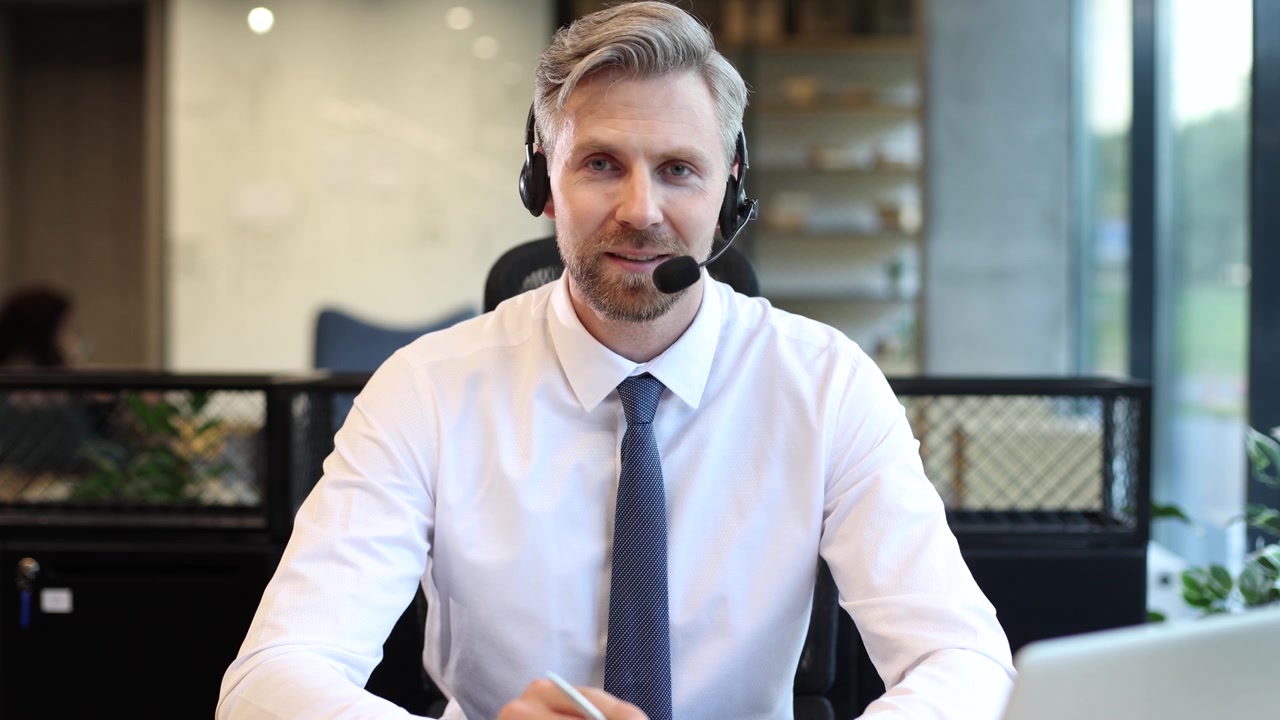 Professionel mand med headset taler under videoopkald på kontoret