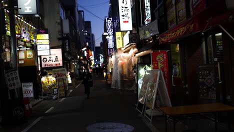 pedestrians walking down a neon-lit urban alley