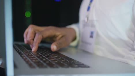 African-american-male-computer-technician-using-laptop-working-in-business-server-room