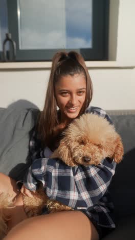 woman cuddling a poodle on a sofa