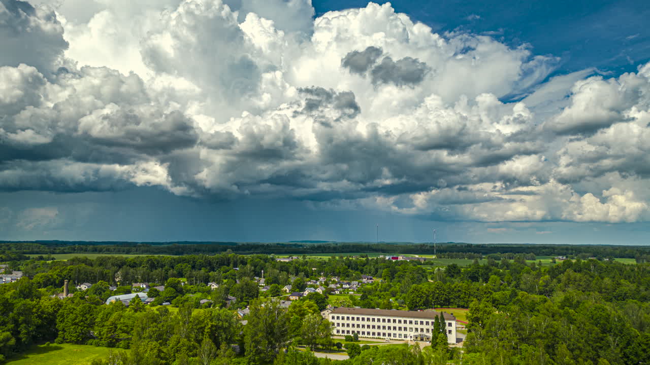 Dramatic cloudscape aerial hyper lapse over a village and green landscape