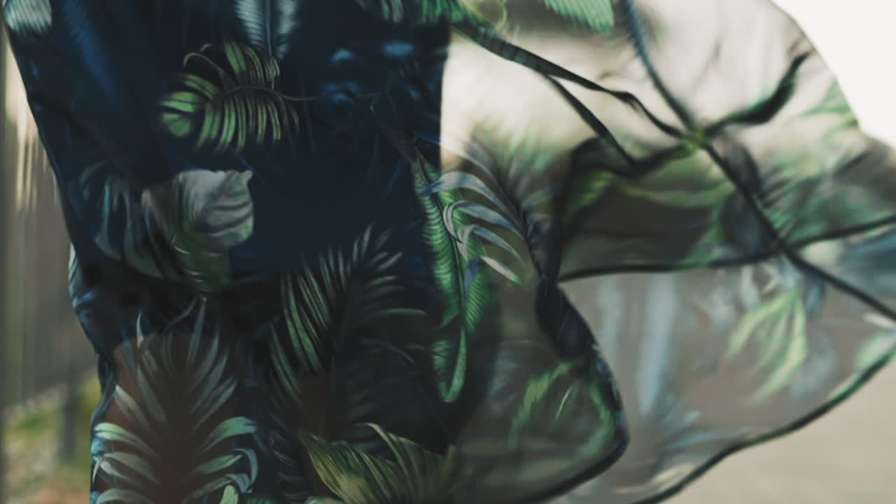 꽃 패턴 을 가진 시폰 스커트 를 입은 여자 가 도로 를 따라  ⁇ 고 있다