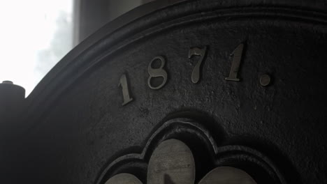 Still-shot-of-a-close-up-of-an-old-printing-press,-metal-face-with-a-year-on-it-with-a-dot