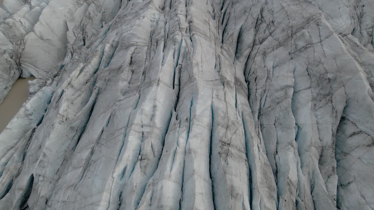 incline hacia arriba desde el patrón de hielo agrietado que revela el impresionante paisaje del glaciar svinafellsjokull, retroceso aéreo
