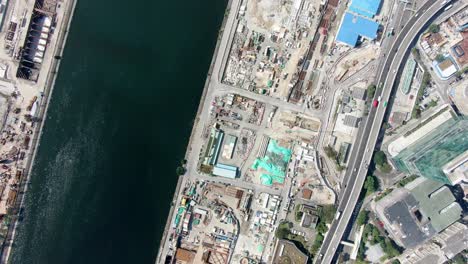 mega construction project of a housing and business district at kai tak downtown hong kong, with vast infrastructure development land and an underwater tunnel laying operation, aerial view