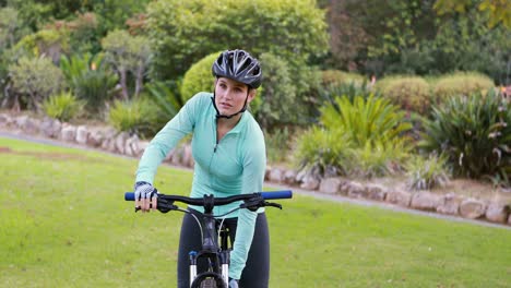 Female-cyclist-drinking-water-in-park