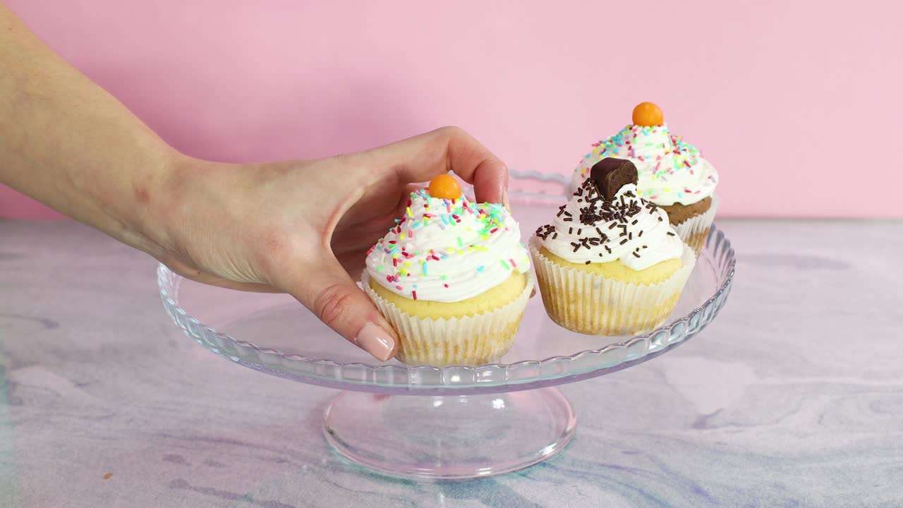 크리스탈 접시에 컵 케이크를 손으로 넣고 생일 파티를 장식합니다.