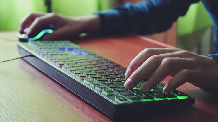 Ung gamer spiller et computerspil og bruger et oplyst gaming-tastatur 01