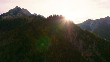 aerial view rising over austrian tyrol alpine woodland mountain peak to reveal sunshine