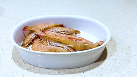 prawns arranged in a white bowl on countertop