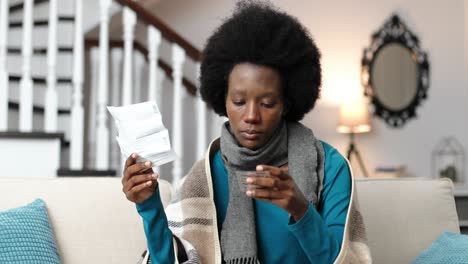 close up portrait of african american female sitting at home on sofa and reading a patient information leaflet