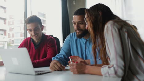 smiling men and woman talking and looking at laptop.