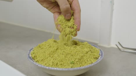 chef puts hand into the plate with chopped nuts