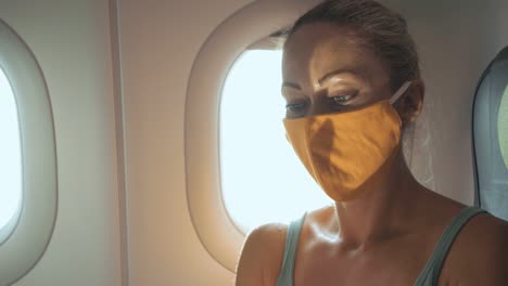 mujer caucásica viajando en avión con máscara médica de protección. chica turista en avión con respirador de protección. coronavirus covid-19