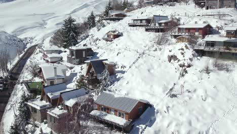 aerial orbit of the european style houses and cabins built on the edge of a completely white and snowy hill on a sunny day, chile