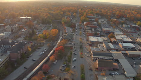 aerial following a passenger train as it pulls into a train station in kirkwood in st