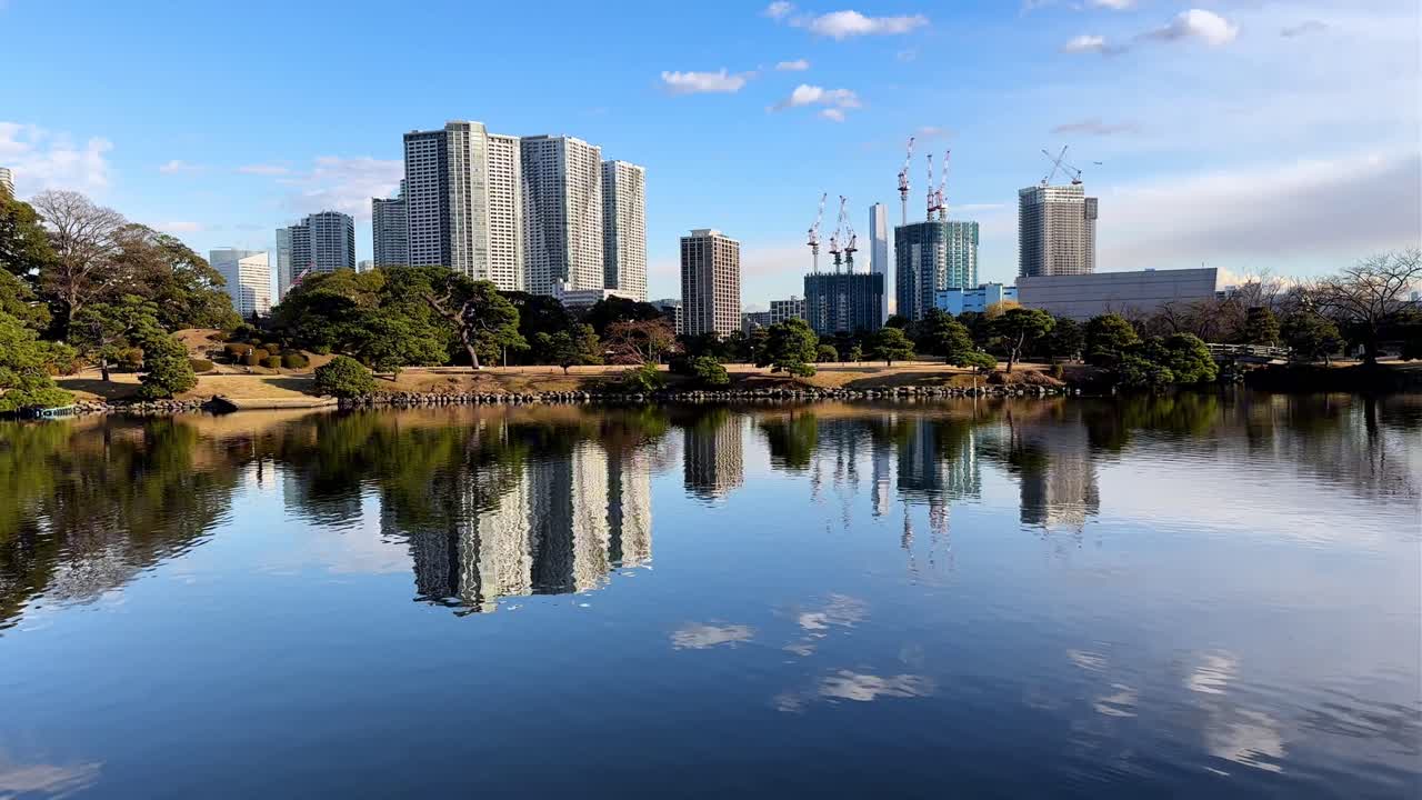 A serene reflection of urban skyscrapers and trees in Hama Rikyu Gardens’ pond