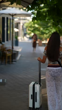 woman with suitcase walking in city