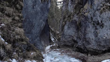 Rückwärts-Durch-Engen-Spalt-Zwischen-Schroffen-Klippen-Mit-Holzbrücke-Im-Winterwald