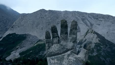 weathered concrete hand sculpture points towards a majestic mountain peak, blending art with the beauty of nature