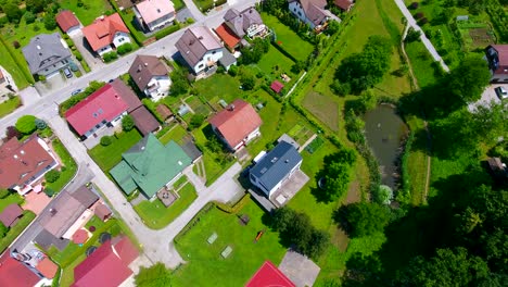 Aerial-Drone-View-Above-Clean-and-Tidy-Green-Neighborhood-of-Celje-Slovenia-Houses-and-Car-Passing-By-Quiet-Road-in-Warm-Sunny-Day