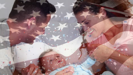 animation of flag of usa and confetti over happy caucasian parents playing with baby