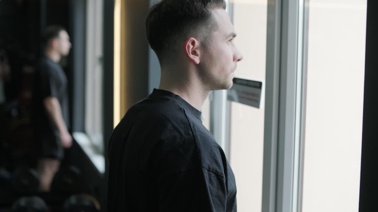 Man Looking Out Window in a Gym