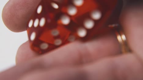 man-shows-and-throws-red-dices-on-light-background-macro