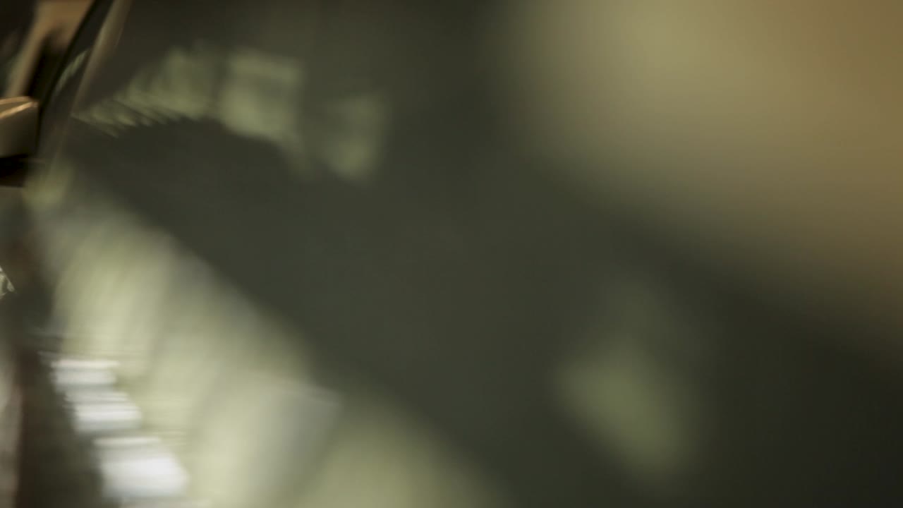 A line of white cars with headlights turning on in a dimly lit garage