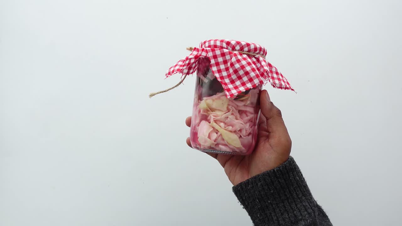 Kädet pitävät kädessään purkkia, jossa on hapankaalia
