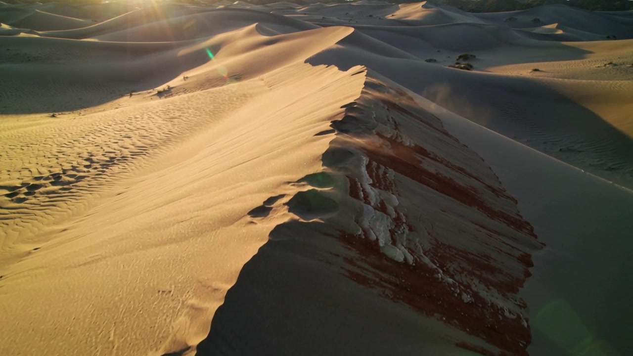 Telecamera drone in movimento che mostra la cresta di una duna di sabbia all'alba, avanzando per rivelare increspature e strati.