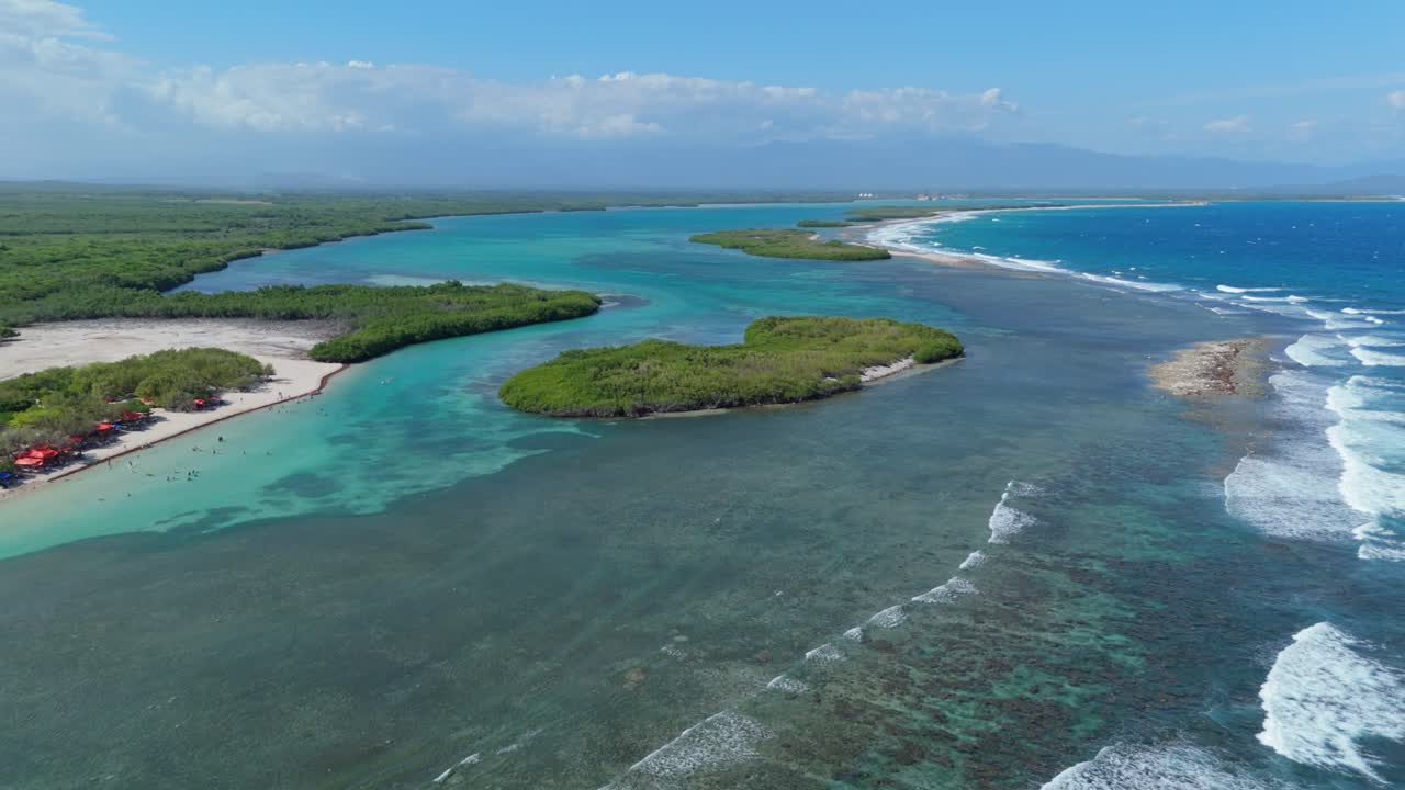 Sandy beach with coral reef below turquoise water of Caribbean sea. Playa Caobita in Dominican Republic. Aerial backwards wide shot.