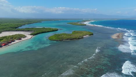 sandy beach with coral reef below turquoise water of caribbean sea. playa caobita in dominican republic. aerial backwards wide shot.