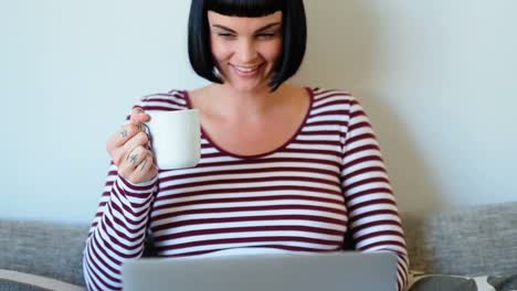 Woman-having-coffee-while-using-laptop-4k