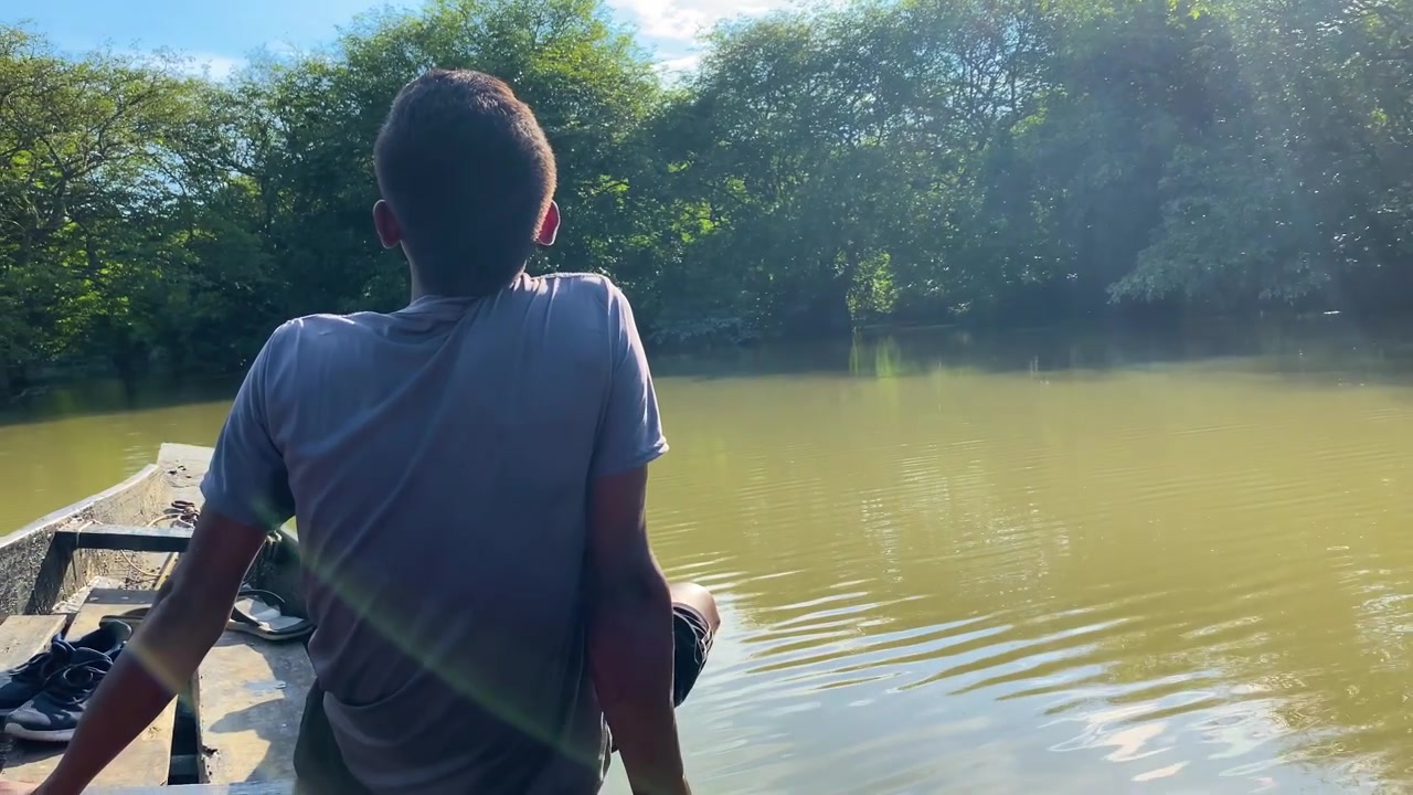 Joven turista sentado en un bote de madera contemplando las aguas del bosque pantanoso de Ratargul, Sylhet, Bangladesh