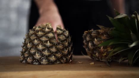 Chef-chopping-off-piece-of-pineapple-with-big-knife-while-little-pieces-are-flying-around,-SLOW-MOTION