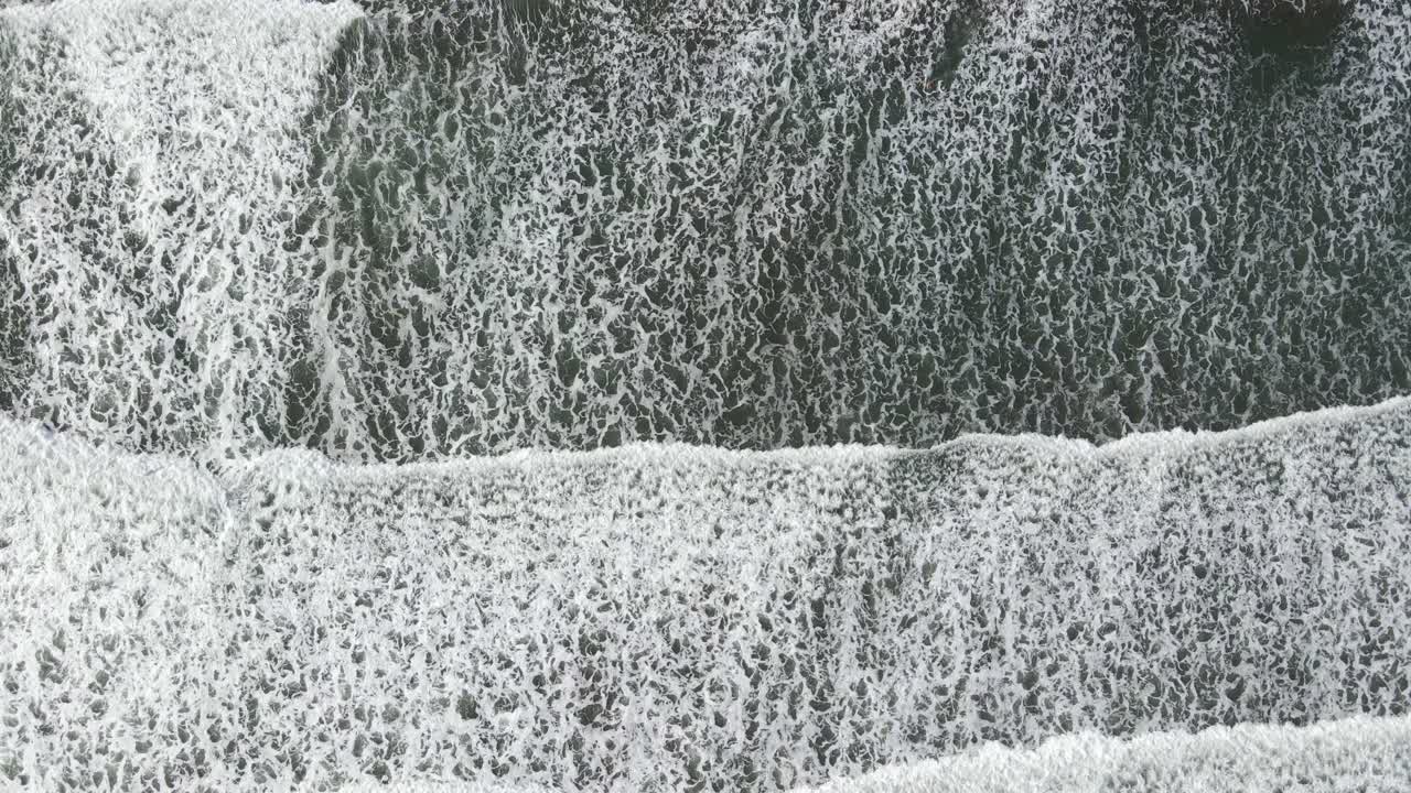 Three waves peacefully crash on the beach