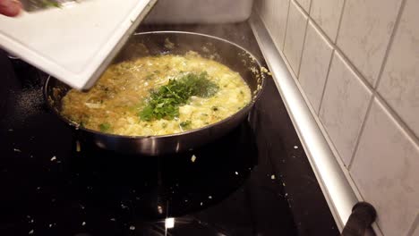 agregar cilantro picado a una sartén con un plato de verduras ya cocinado en él