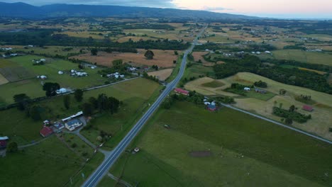 Chiloé's-route-with-vast-farmlands-at-dusk,-serene-landscape,-aerial-view