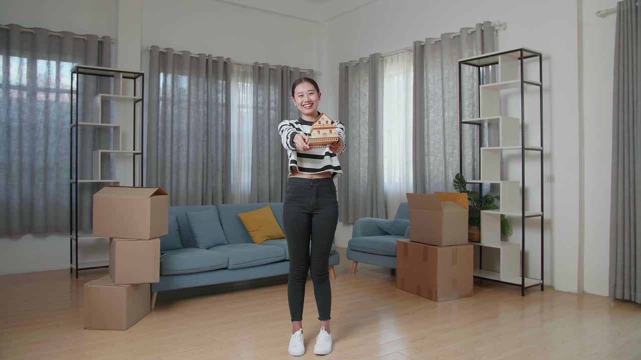 행복 한 여자 는 새 집 에서 집 모델 을 들고 있다