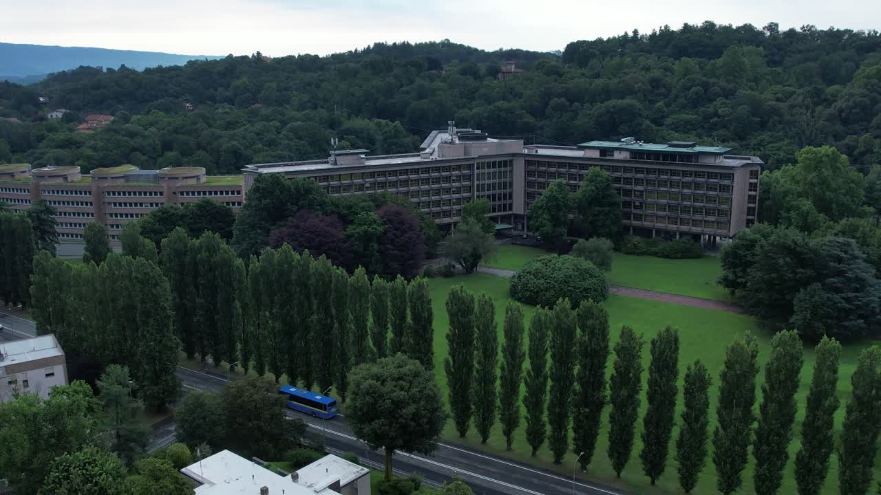 Drone view of the Nuovo Palazzo Uffici Olivetti by architect Gino Valle in Ivrea, Italy, hallmark of modernist corporate architecture now used by TIM, framed by green lawns, drone, slow motion.