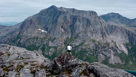hombre de pie y admirando la vista en el borde de la montaña rocosa de salberget en flakstadvag, noruega