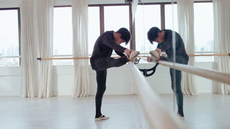 male ballet dancer stretching at the barre in studio