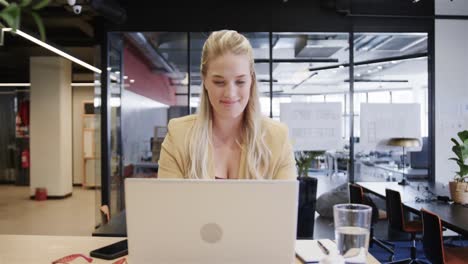 Happy-plus-size-caucasian-casual-businesswoman-using-laptop-at-desk